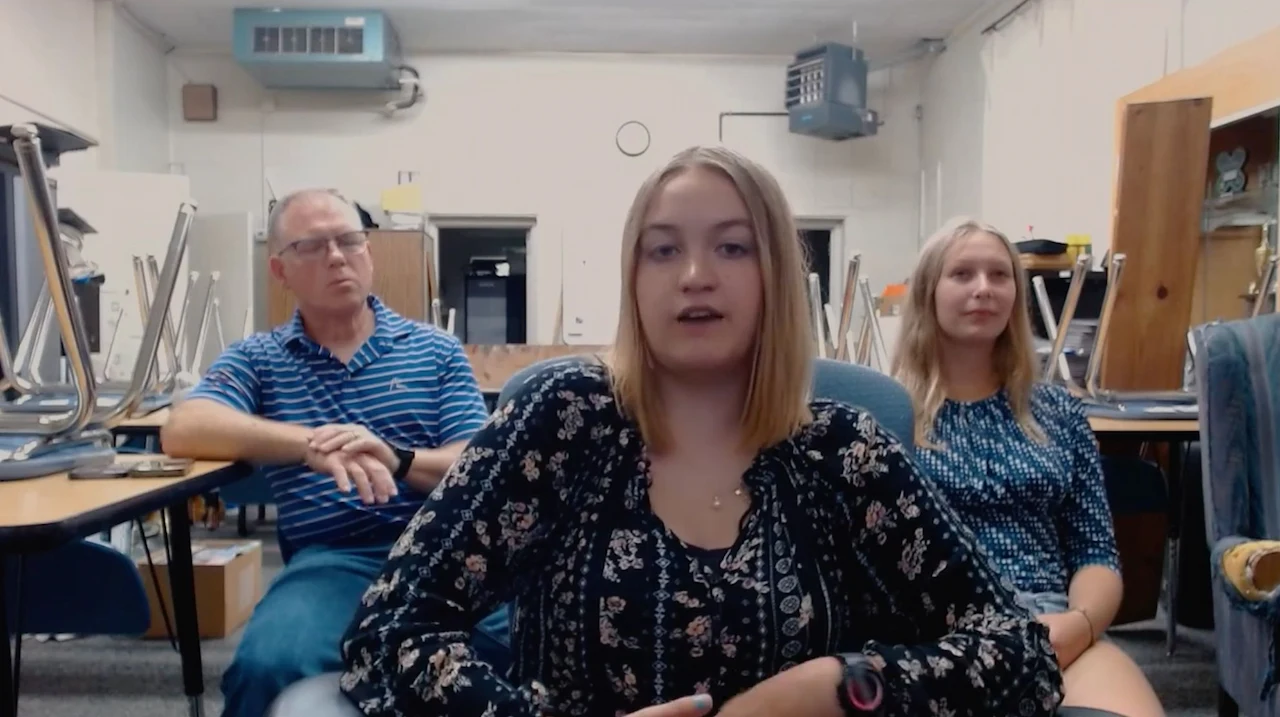 Three people sitting in a classroom setting.