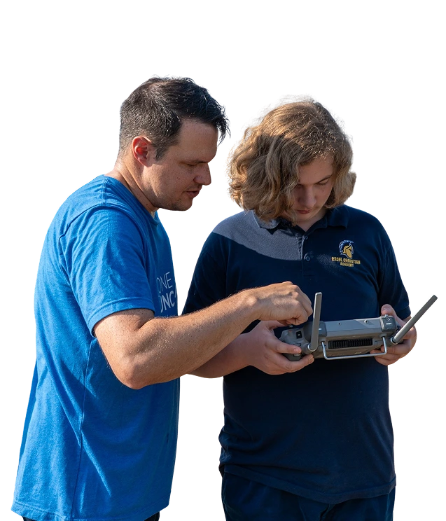 Instructor teaches student drone operation outdoors.