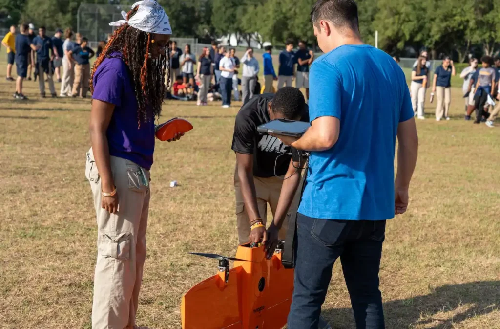 People assembling an orange drone outdoors.
