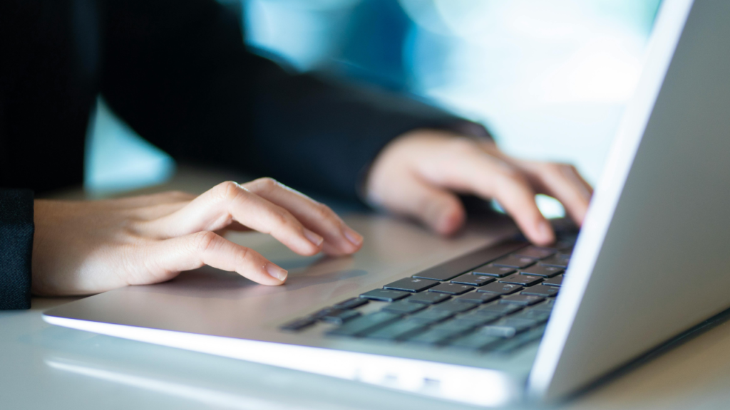 Hands typing on a laptop keyboard
