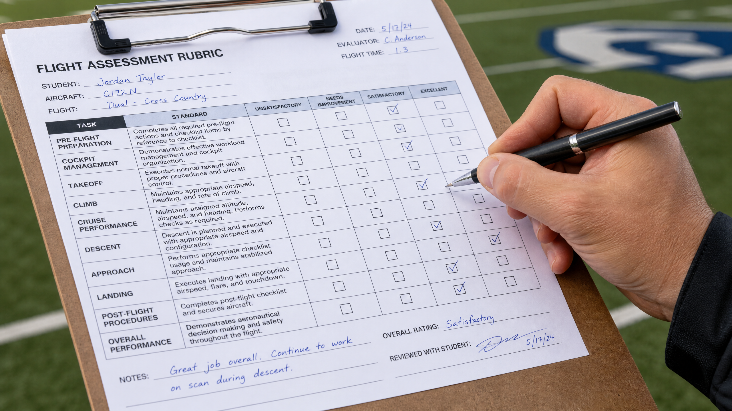 Teacher's hand marking a detailed flight assessment rubric on a clipboard at a school athletic field